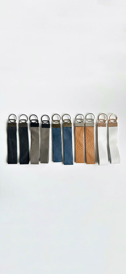 Genuine leather ketchain wristlets in multiple colors. Navy blue, black, tan, gray, and white.