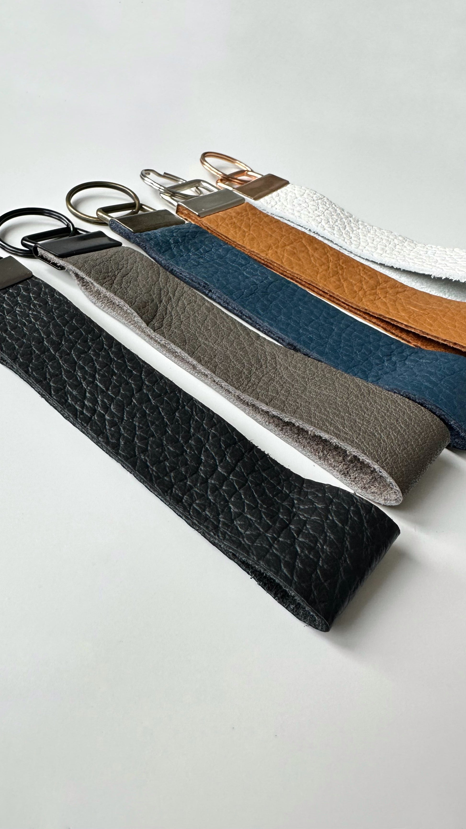 Genuine leather ketchain wristlets in multiple colors. Navy blue, black, tan, gray, and white.